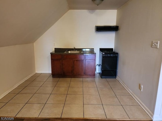 kitchen with black gas range oven, a sink, lofted ceiling, range hood, and light tile patterned floors