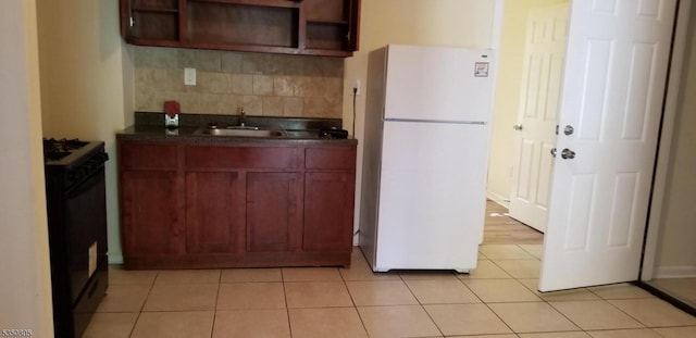 kitchen with freestanding refrigerator, black gas range, open shelves, dark countertops, and decorative backsplash