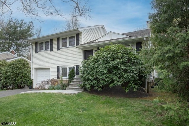 split level home with an attached garage, a front lawn, and driveway