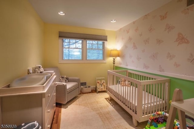carpeted bedroom featuring a nursery area, wallpapered walls, visible vents, and recessed lighting