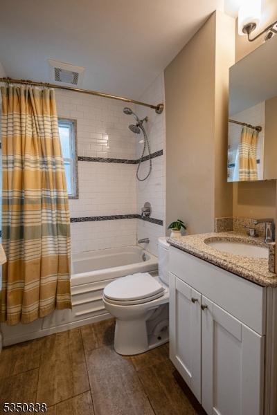 full bathroom featuring visible vents, wood finished floors, toilet, and shower / bath combo with shower curtain