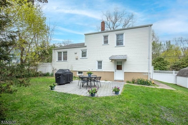 back of house featuring fence, a chimney, a lawn, and a patio area