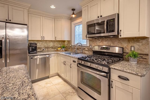 kitchen featuring light stone countertops, a sink, stainless steel appliances, recessed lighting, and backsplash