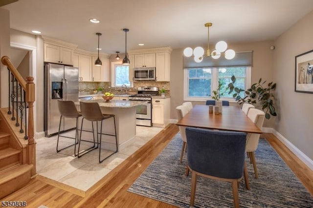 dining space featuring an inviting chandelier, recessed lighting, stairs, and light wood finished floors