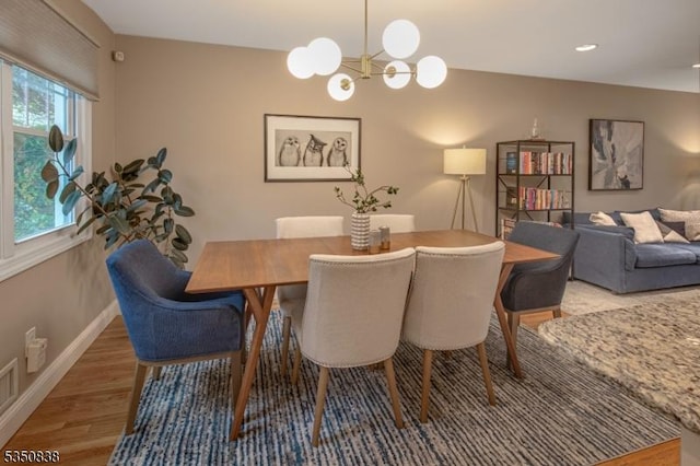 dining space with an inviting chandelier, baseboards, and light wood-type flooring