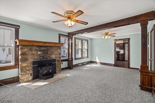 unfurnished living room featuring carpet flooring, a ceiling fan, a wood stove, baseboards, and beam ceiling