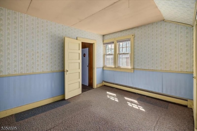 spare room with baseboard heating, wainscoting, and wallpapered walls