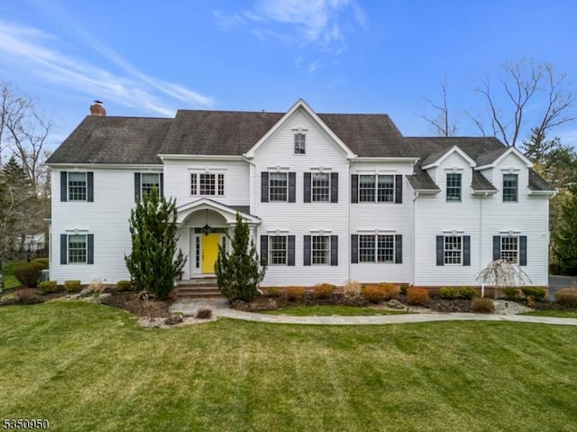 colonial-style house with a chimney and a front lawn