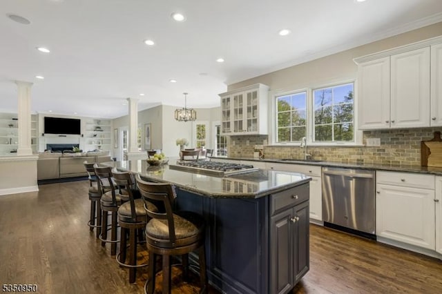 kitchen with ornate columns, white cabinetry, a sink, dark wood finished floors, and appliances with stainless steel finishes