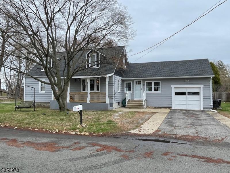 24 N 2nd St, Kenvil, Roxbury Twp, NJ 07847 - cape cod house featuring aphalt driveway, a porch, fence, an attached garage, and a shingled roof