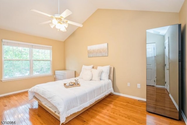 bedroom featuring light wood-type flooring, lofted ceiling, baseboards, and ceiling fan
