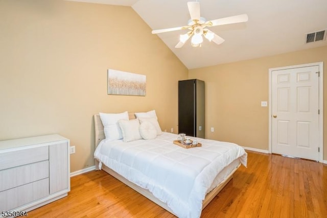 bedroom featuring light wood finished floors, lofted ceiling, baseboards, and a ceiling fan