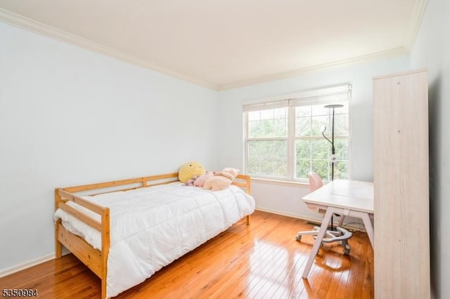 bedroom with ornamental molding, hardwood / wood-style flooring, baseboards, and a desk