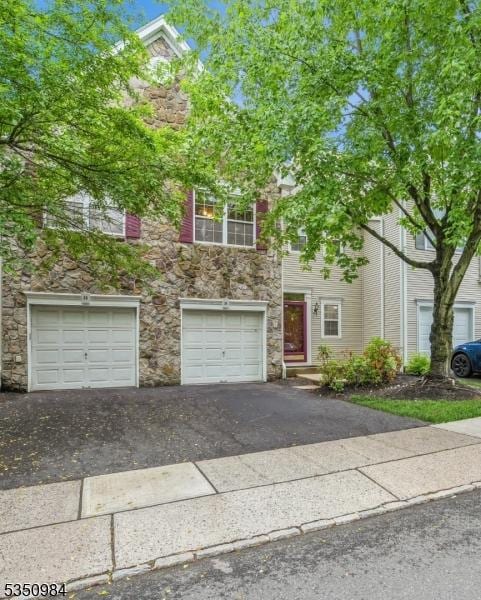 view of front facade with stone siding, driveway, and a garage