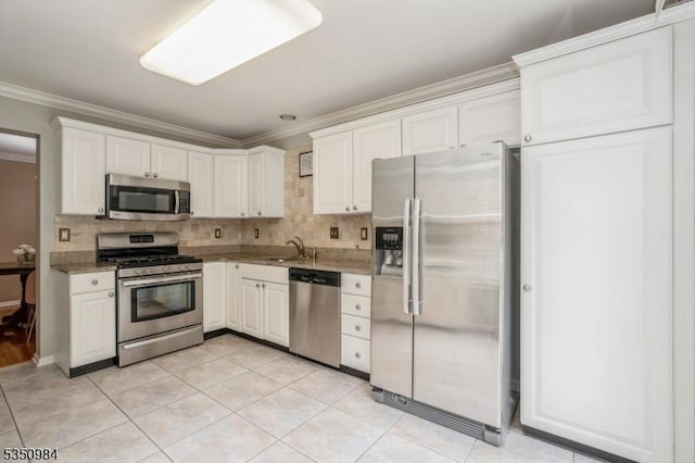 kitchen with appliances with stainless steel finishes, crown molding, a sink, tasteful backsplash, and white cabinetry