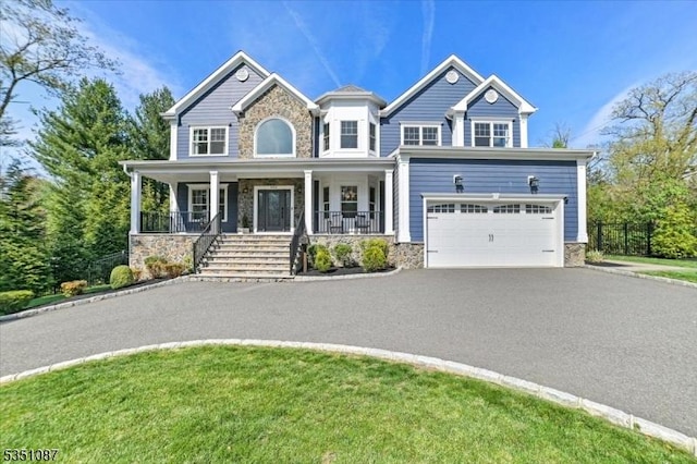 view of front of house with covered porch, driveway, and stone siding