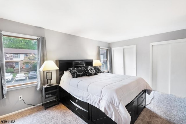 carpeted bedroom featuring two closets and baseboards