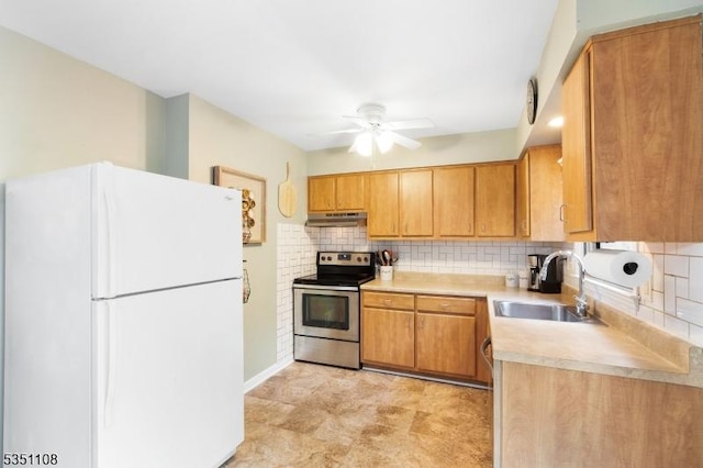 kitchen featuring freestanding refrigerator, stainless steel electric stove, a sink, under cabinet range hood, and light countertops