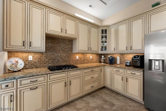 kitchen with black gas stovetop, cream cabinetry, stainless steel fridge with ice dispenser, and tasteful backsplash