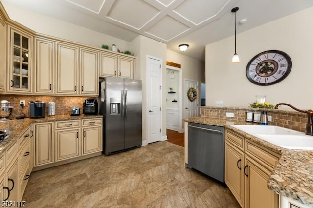 kitchen featuring cream cabinetry, tasteful backsplash, a sink, hanging light fixtures, and stainless steel appliances