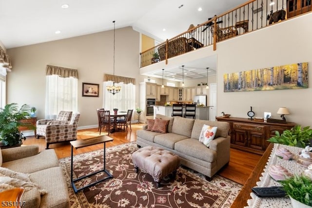 living room with high vaulted ceiling, light wood finished floors, and a notable chandelier