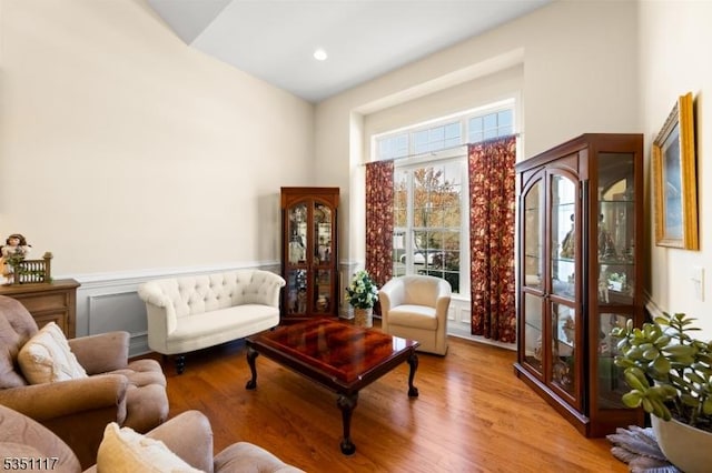 living area with wainscoting, wood finished floors, and a towering ceiling