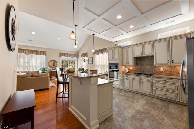 kitchen featuring appliances with stainless steel finishes, recessed lighting, open floor plan, cream cabinetry, and a kitchen bar