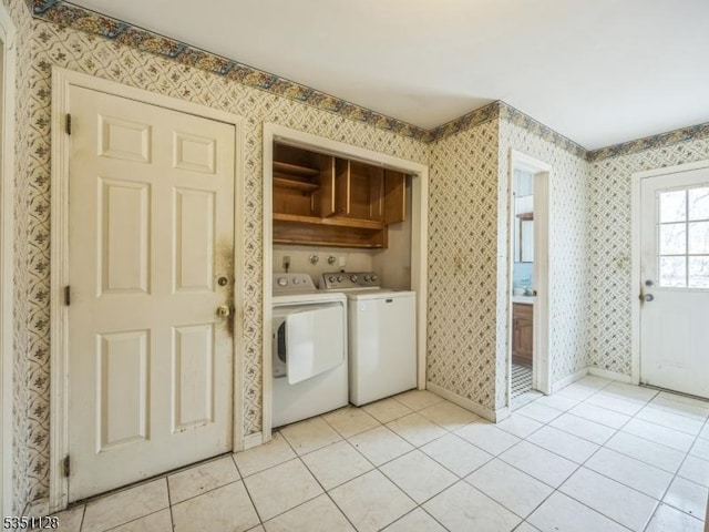 laundry room with wallpapered walls, light tile patterned floors, washing machine and dryer, baseboards, and cabinet space
