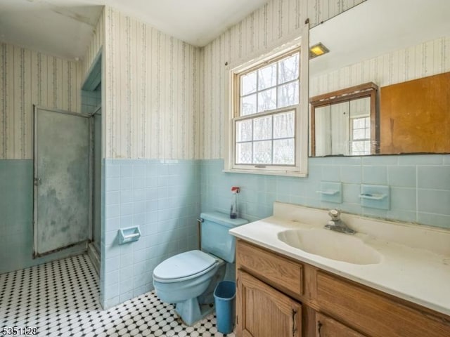 bathroom with wainscoting, wallpapered walls, and a shower stall