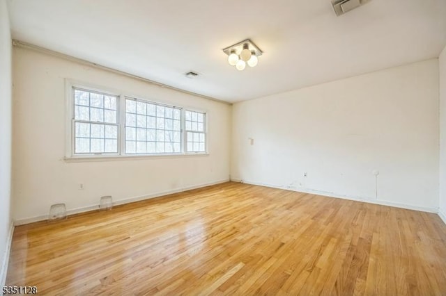 unfurnished room featuring baseboards, light wood finished floors, and visible vents