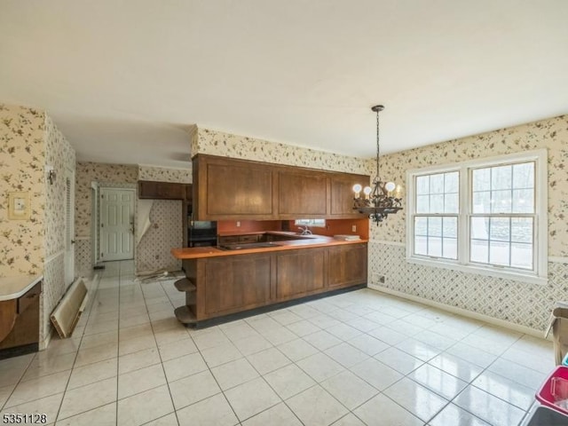 kitchen featuring wallpapered walls, a peninsula, a notable chandelier, and light tile patterned floors