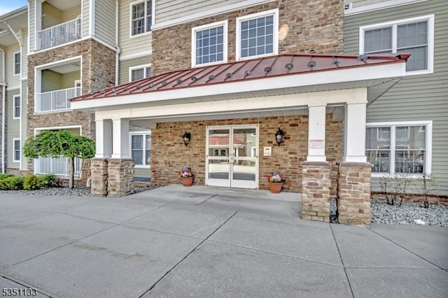 entrance to property with stone siding and a standing seam roof