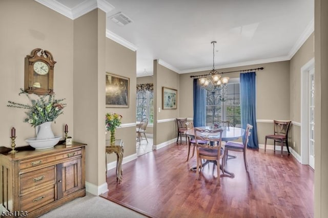 dining space featuring a chandelier, healthy amount of natural light, ornamental molding, light wood finished floors, and baseboards
