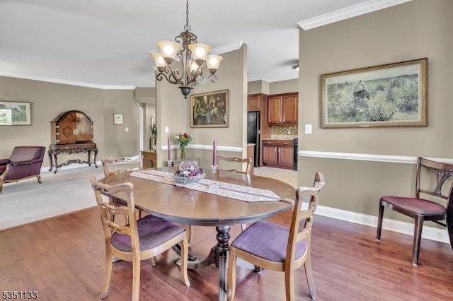dining space featuring a chandelier, ornamental molding, light wood-style flooring, and baseboards