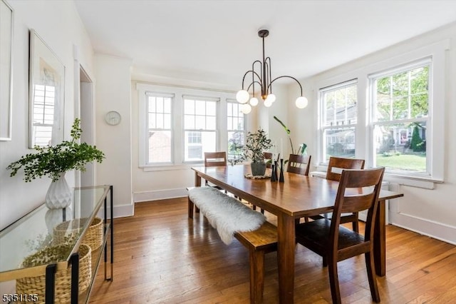 dining space featuring baseboards, wood-type flooring, and a notable chandelier