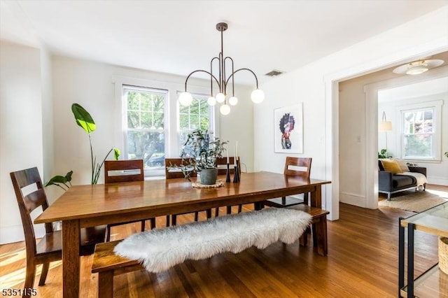 dining space featuring visible vents, light wood finished floors, and a notable chandelier