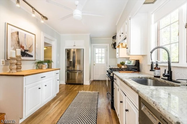 kitchen with a sink, white cabinetry, wooden counters, and stainless steel appliances
