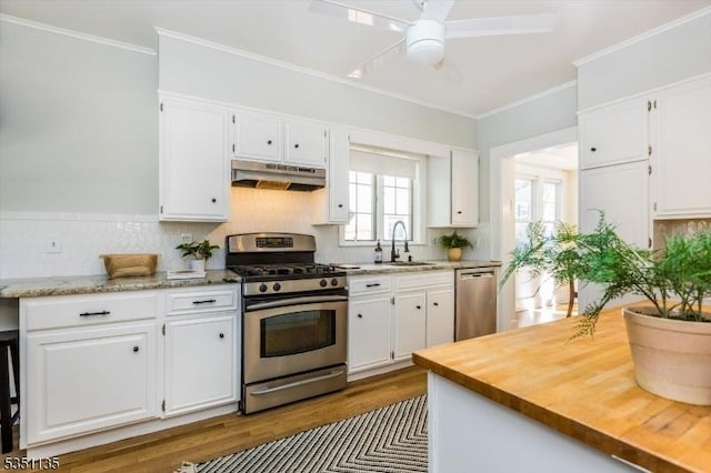 kitchen with a sink, white cabinets, stainless steel appliances, and under cabinet range hood