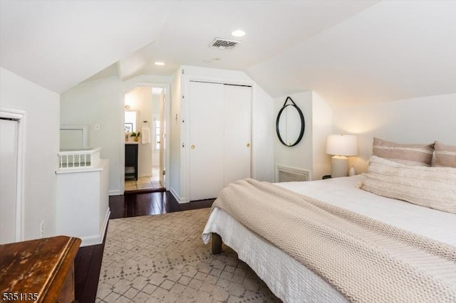 bedroom featuring visible vents, wood finished floors, lofted ceiling, and a closet
