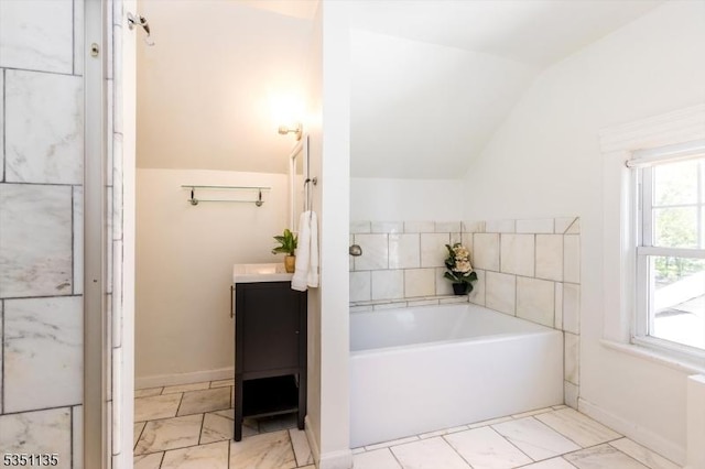 bathroom featuring vanity, marble finish floor, a bath, and lofted ceiling