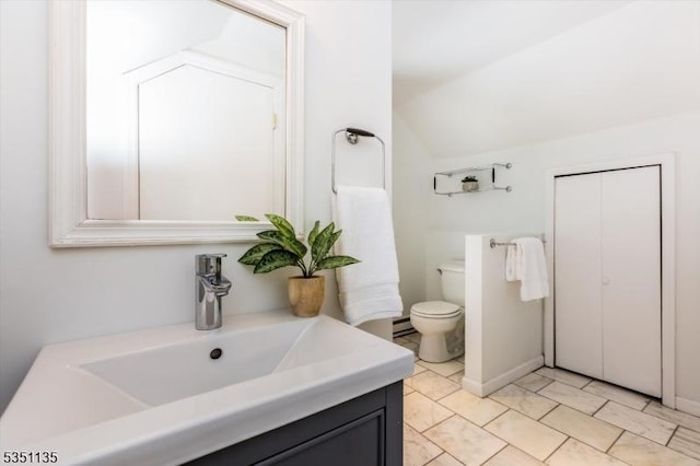 bathroom featuring toilet, vaulted ceiling, and vanity