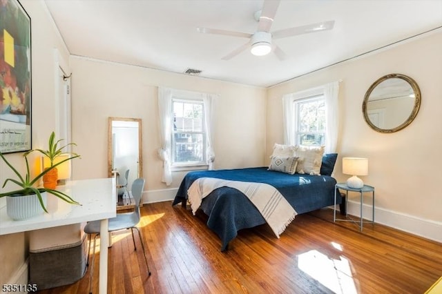 bedroom with baseboards, visible vents, multiple windows, and hardwood / wood-style floors