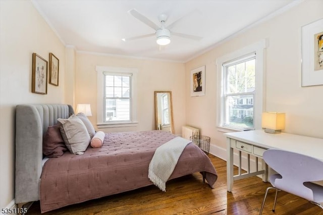 bedroom with ornamental molding, radiator, wood finished floors, baseboards, and ceiling fan