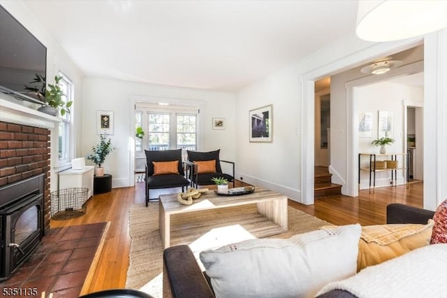 living area with baseboards, a wood stove, and wood finished floors