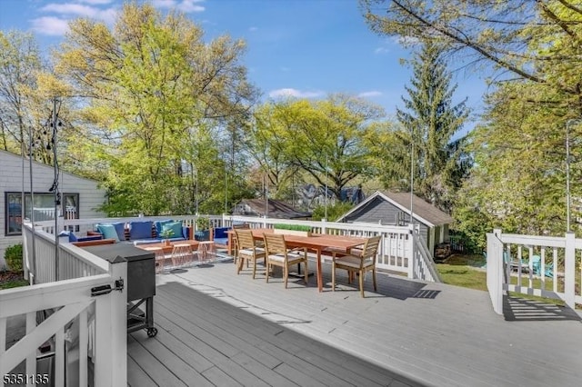 wooden deck featuring outdoor dining area, an outbuilding, and an outdoor hangout area