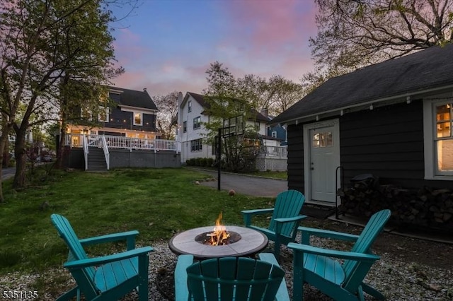 yard at dusk with a deck, a fire pit, and stairs