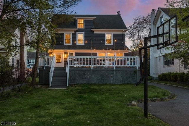 rear view of property featuring stairs, a yard, and a deck