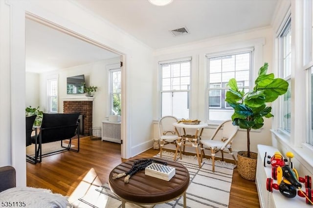 living area with visible vents, ornamental molding, and wood finished floors