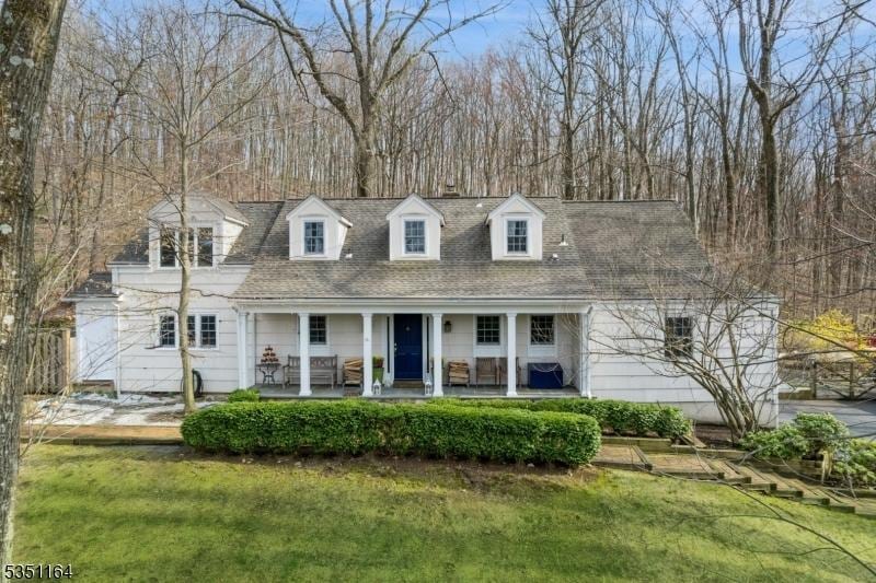view of front of house featuring a porch, a shingled roof, and a front yard