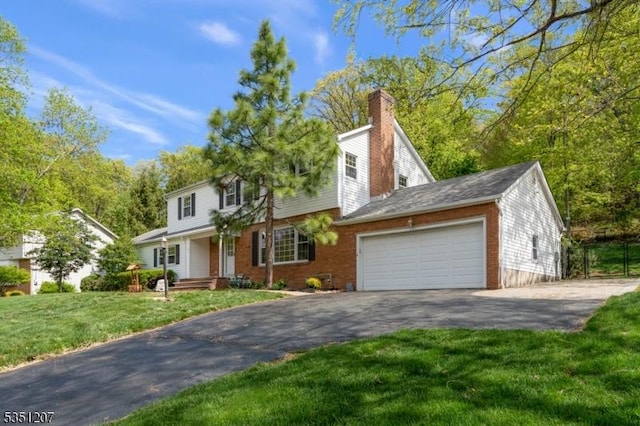 view of front of house with aphalt driveway, a front yard, a chimney, brick siding, and an attached garage